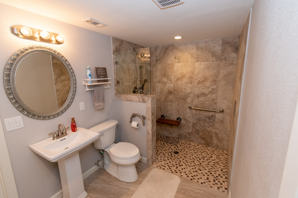 This is an example of a medium sized classic bathroom in Houston with a built-in shower, a two-piece toilet, grey walls, porcelain flooring, a pedestal sink, brown floors, an open shower, a shower bench and a single sink.