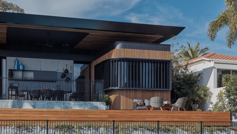 Contemporary backyard deck in Gold Coast - Tweed with an outdoor kitchen and a roof extension.