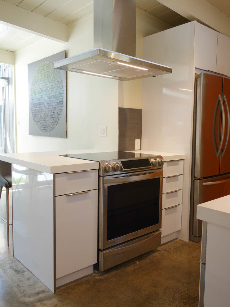 Photo of a mid-sized midcentury galley eat-in kitchen in San Francisco with an undermount sink, flat-panel cabinets, white cabinets, quartz benchtops, grey splashback, ceramic splashback, stainless steel appliances, concrete floors, with island, grey floor and white benchtop.