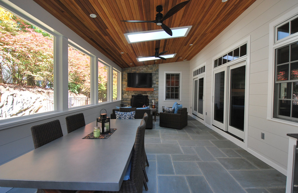 This is an example of a mid-sized contemporary sunroom in Boston with slate floors, a standard fireplace, a stone fireplace surround, a skylight and blue floor.