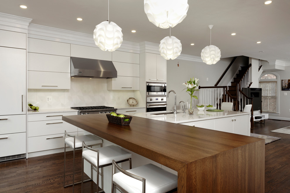 This is an example of a large contemporary l-shaped eat-in kitchen in DC Metro with an undermount sink, flat-panel cabinets, white cabinets, wood benchtops, white splashback, stainless steel appliances, dark hardwood floors, with island, porcelain splashback and brown floor.