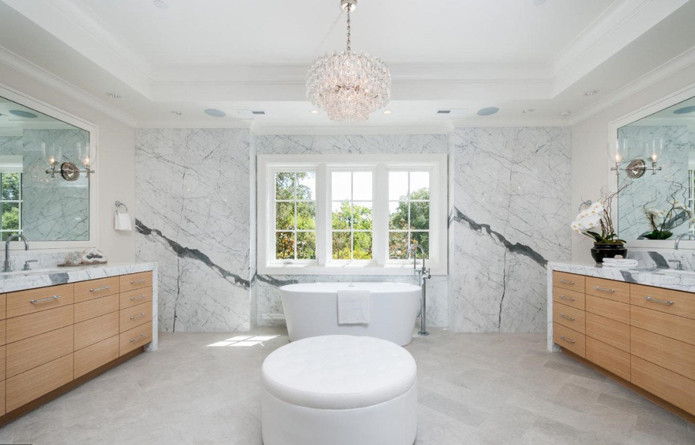 Transitional freestanding bathtub photo with flat-panel cabinets, light wood cabinets and white walls