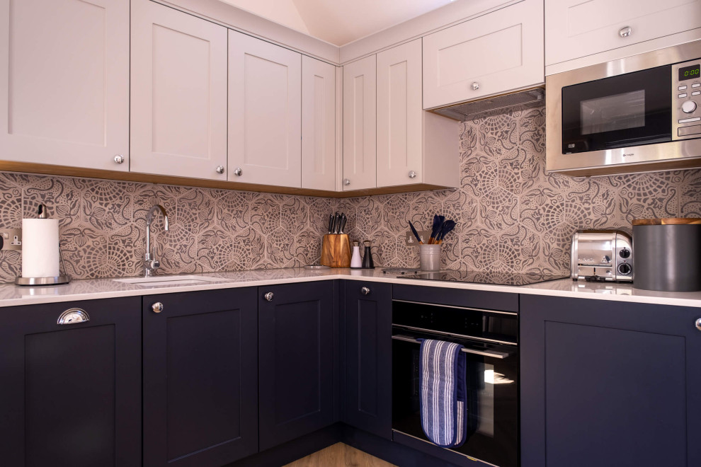 Inspiration for a small country kitchen in Hampshire with an undermount sink, shaker cabinets, blue cabinets, quartz benchtops, grey splashback, ceramic splashback, stainless steel appliances, laminate floors, brown floor, white benchtop and vaulted.