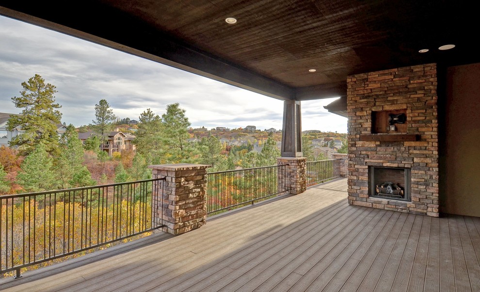Inspiration for a large modern backyard deck in Denver with a fire feature and a roof extension.