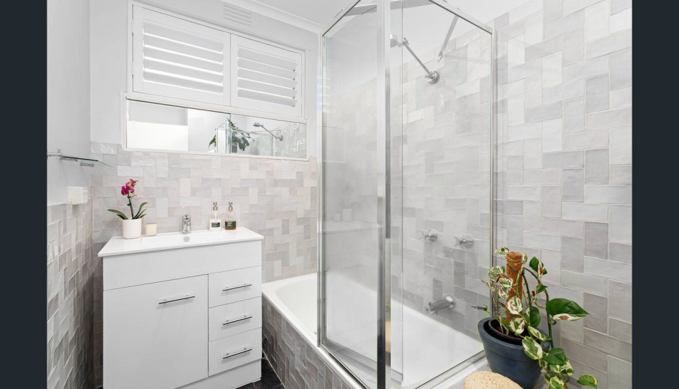 Inspiration for a small contemporary bathroom in Brisbane with freestanding cabinets, white cabinets, a built-in bath, grey tiles, ceramic tiles, grey walls, slate flooring, solid surface worktops, black floors, a hinged door, white worktops, a single sink and a freestanding vanity unit.