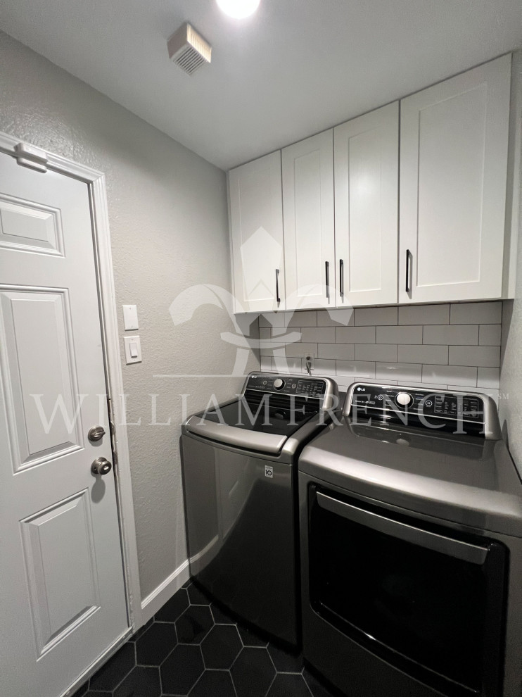 This is an example of a small modern single-wall dedicated laundry room in Dallas with shaker cabinets, white cabinets, white splashback, subway tile splashback, grey walls, porcelain floors, a side-by-side washer and dryer and black floor.