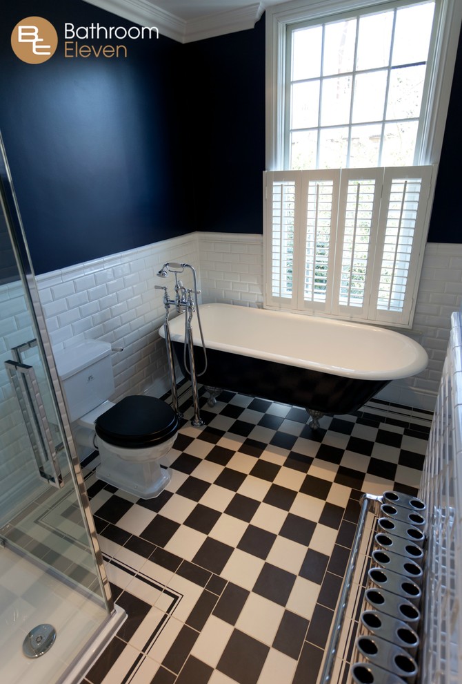 Design ideas for a mid-sized traditional bathroom with a freestanding tub, an open shower, a two-piece toilet, black and white tile, glass sheet wall, black walls and ceramic floors.