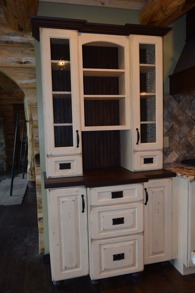 Inspiration for a rustic u-shaped dark wood floor eat-in kitchen remodel with a farmhouse sink, raised-panel cabinets, white cabinets, granite countertops, beige backsplash, stone tile backsplash, stainless steel appliances and an island