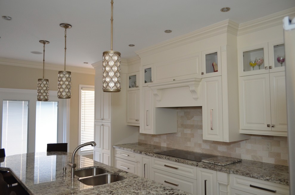 Mid-sized transitional l-shaped porcelain tile enclosed kitchen photo in Toronto with an undermount sink, raised-panel cabinets, white cabinets, granite countertops, beige backsplash, stainless steel appliances and an island
