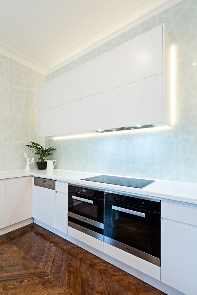 Contemporary l-shaped eat-in kitchen in Melbourne with an integrated sink, flat-panel cabinets, white cabinets, marble benchtops, grey splashback, glass sheet splashback and with island.
