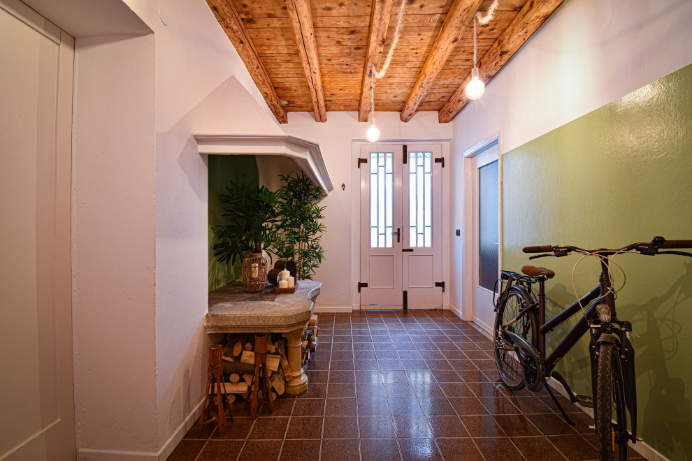 Пример оригинального дизайна: маленькая входная дверь в стиле рустика с белыми стенами, полом из керамической плитки, двустворчатой входной дверью, белой входной дверью, коричневым полом и балками на потолке для на участке и в саду