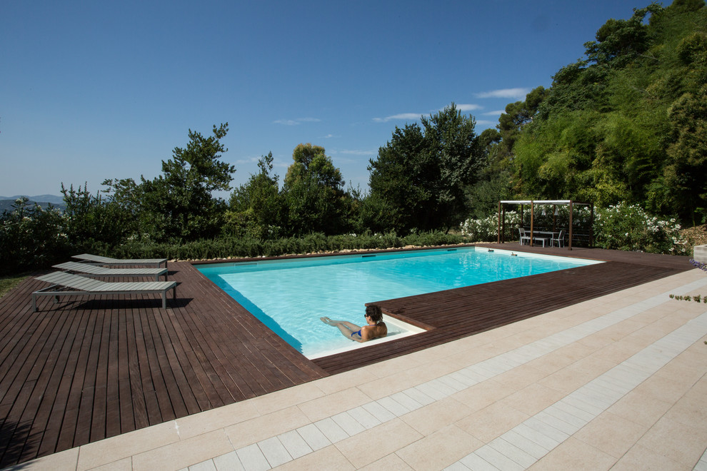 Photo of a large mediterranean front yard l-shaped pool in Other with a pool house and decking.