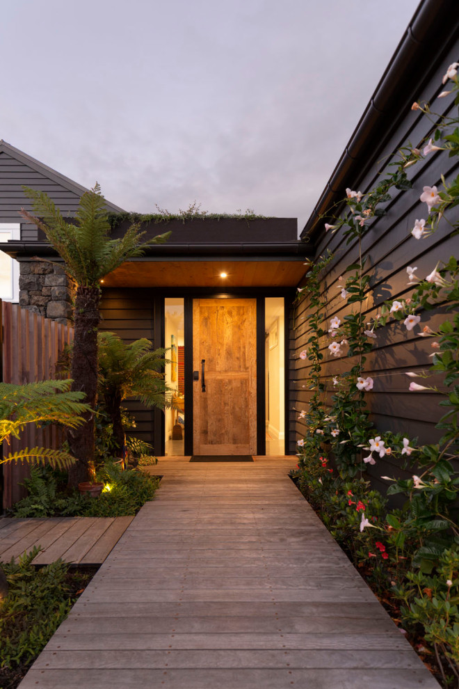 Große Moderne Haustür mit schwarzer Wandfarbe, hellem Holzboden, Einzeltür, hellbrauner Holzhaustür, beigem Boden, Holzdielendecke und Holzwänden in Auckland