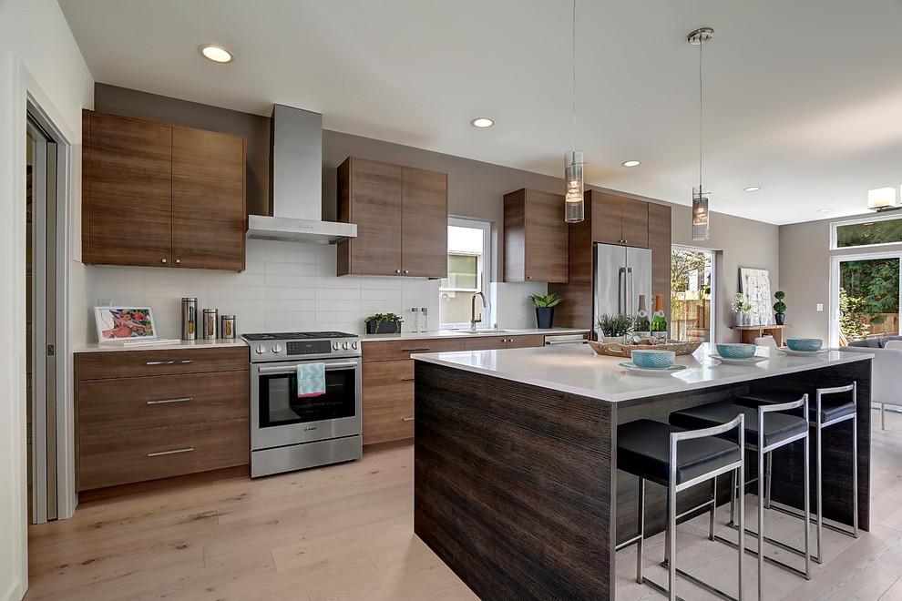Inspiration for a modern kitchen in Seattle with a single-bowl sink, raised-panel cabinets, brown cabinets, quartz benchtops, white splashback, porcelain splashback, vinyl floors and with island.