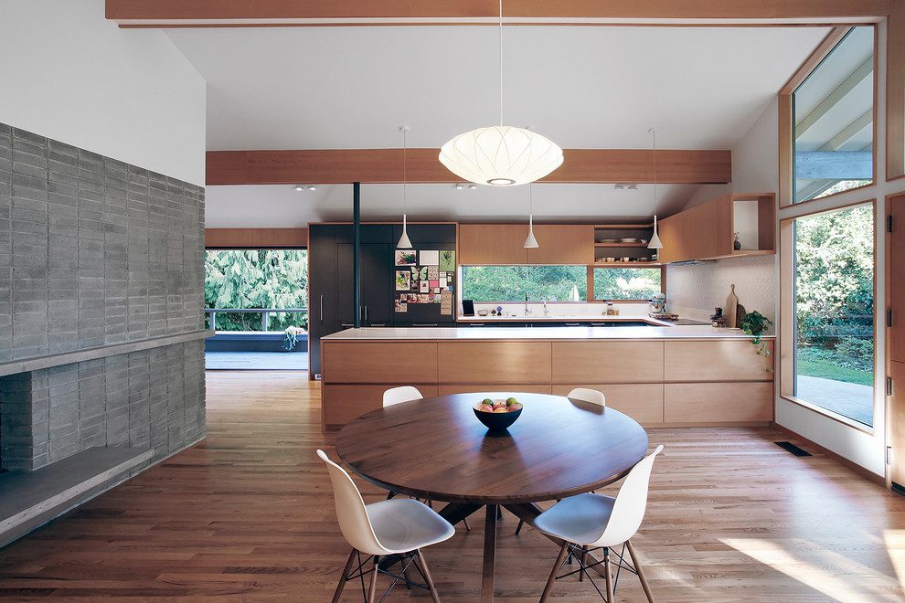 Design ideas for a mid-sized midcentury open plan dining in Seattle with medium hardwood floors, white walls, a standard fireplace, a concrete fireplace surround and brown floor.