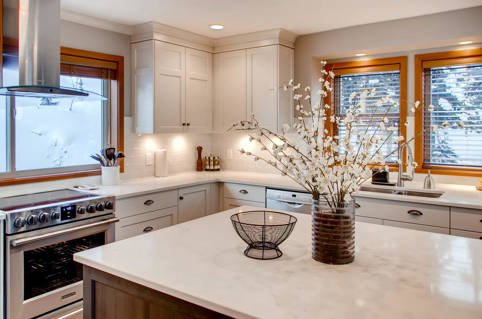 Example of a mid-sized transitional l-shaped enclosed kitchen design with a double-bowl sink, shaker cabinets, white cabinets, marble countertops, white backsplash, subway tile backsplash, stainless steel appliances and an island