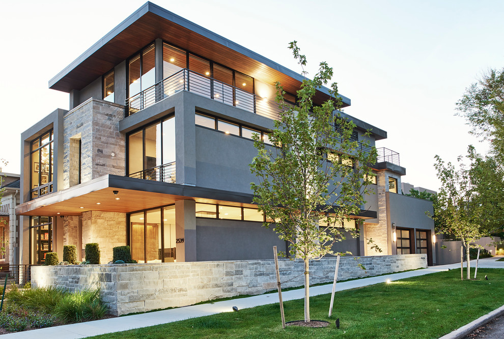Mid-sized modern three-storey grey house exterior in Denver with stone veneer and a flat roof.