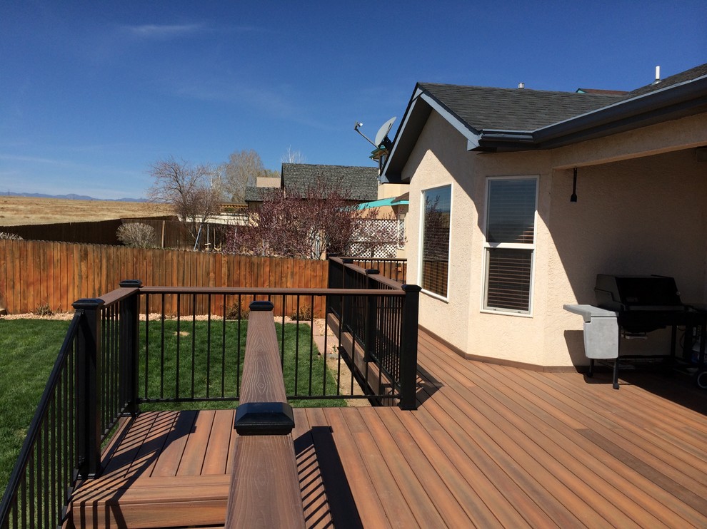 Inspiration for a large transitional backyard deck remodel in Denver with a roof extension