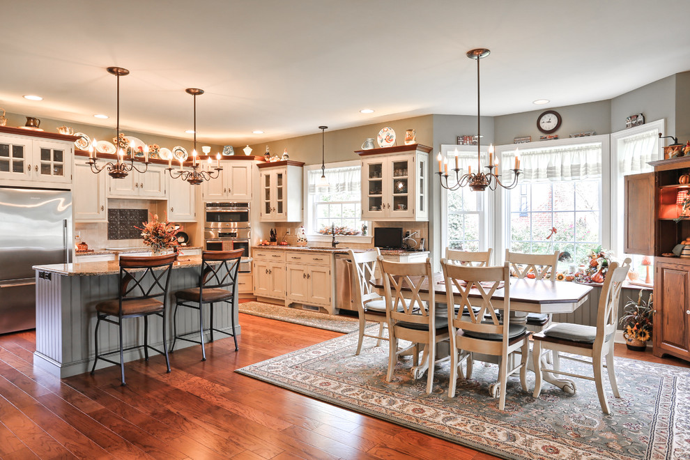 Design ideas for a traditional l-shaped eat-in kitchen in Other with granite benchtops, stainless steel appliances, medium hardwood floors, recessed-panel cabinets, white cabinets and with island.