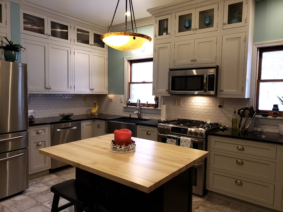 Large transitional u-shaped ceramic tile and beige floor kitchen pantry photo with a farmhouse sink, recessed-panel cabinets, gray cabinets, quartz countertops, white backsplash, subway tile backsplash, stainless steel appliances, an island and black countertops