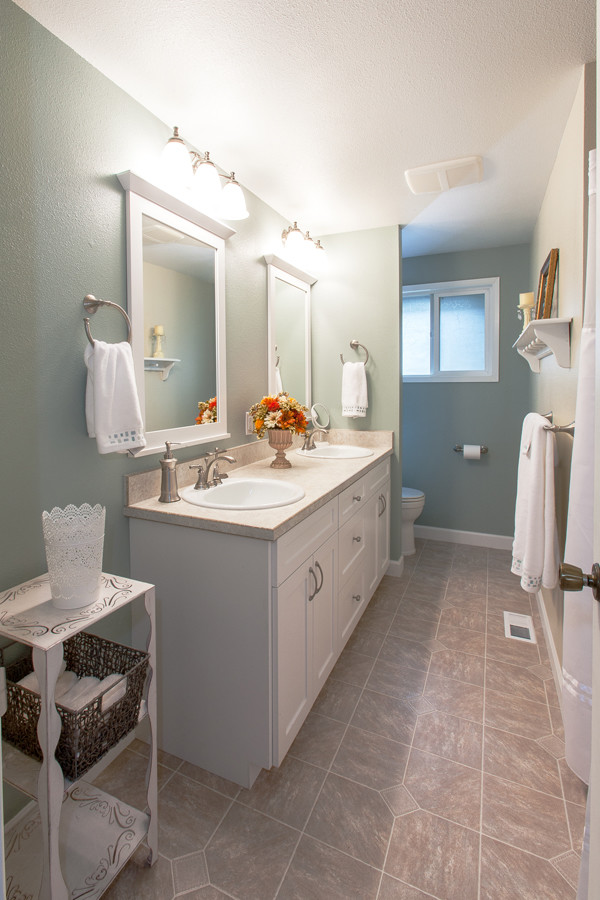 This is an example of a contemporary bathroom in Portland with a drop-in sink, recessed-panel cabinets, white cabinets, laminate benchtops, a shower/bathtub combo and a one-piece toilet.