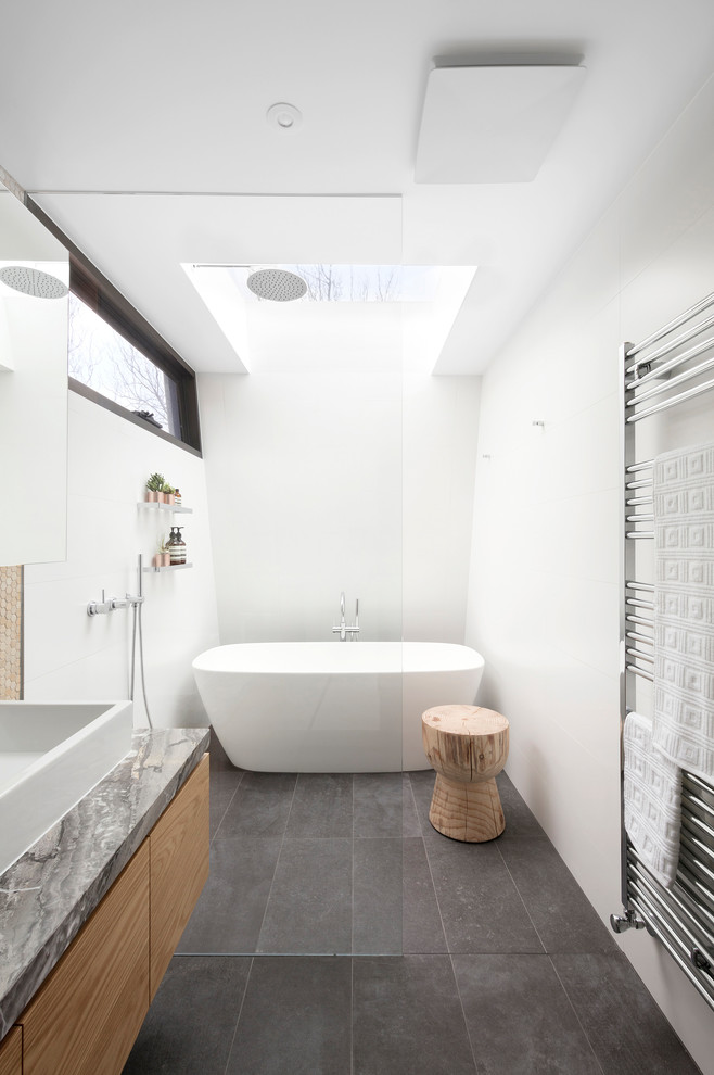 This is an example of a mid-sized contemporary master bathroom in Melbourne with flat-panel cabinets, medium wood cabinets, a freestanding tub, an open shower, a wall-mount toilet, white tile, ceramic tile, white walls, porcelain floors, a vessel sink, marble benchtops, grey floor and an open shower.