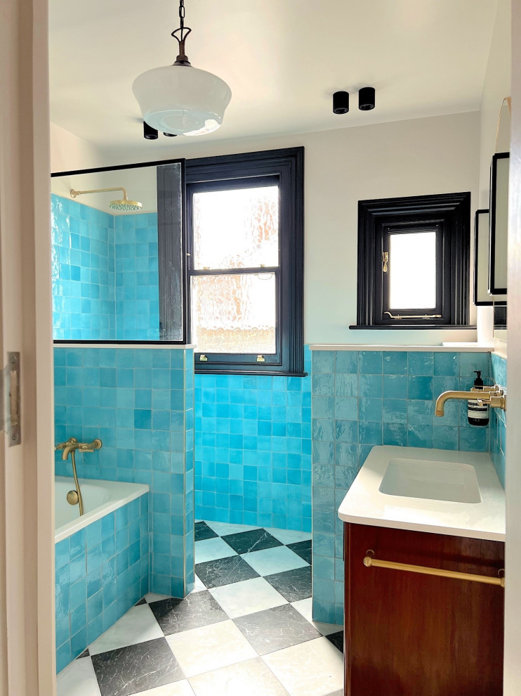 Photo of a mid-sized transitional kids bathroom in London with shaker cabinets, brown cabinets, a drop-in tub, an open shower, a one-piece toilet, blue tile, ceramic tile, blue walls, marble floors, a drop-in sink, quartzite benchtops, multi-coloured floor, an open shower, white benchtops, an enclosed toilet, a single vanity and a freestanding vanity.