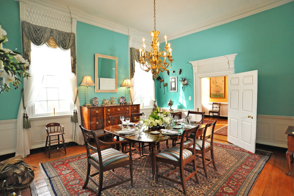 This is an example of a traditional separate dining room in DC Metro with green walls, medium hardwood floors, a standard fireplace, a plaster fireplace surround and brown floor.