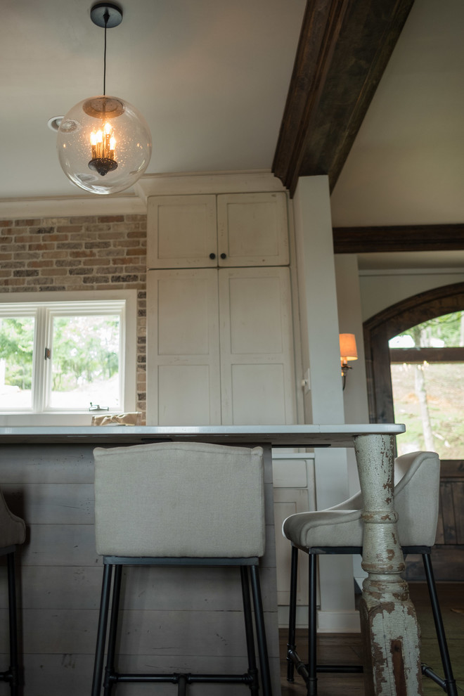 Large transitional galley dark wood floor and brown floor open concept kitchen photo with a farmhouse sink, shaker cabinets, quartz countertops, brown backsplash, brick backsplash, stainless steel appliances and an island