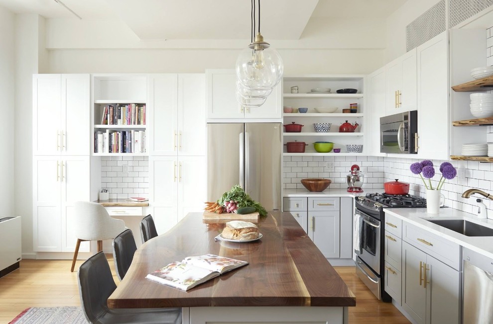 Inspiration for a large transitional l-shaped kitchen in New York with a drop-in sink, shaker cabinets, grey cabinets, subway tile splashback, stainless steel appliances, light hardwood floors, with island and beige floor.