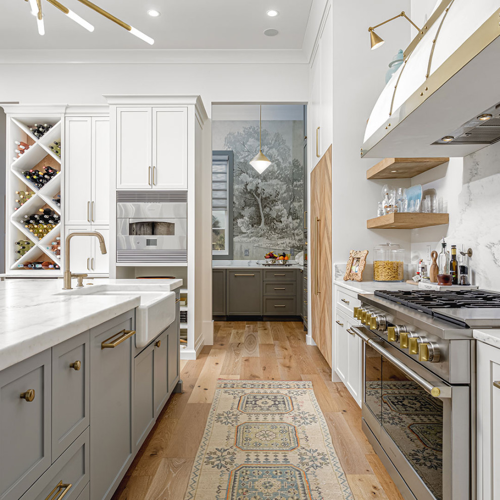 Kitchen - light wood floor kitchen idea with a farmhouse sink, white backsplash, stainless steel appliances and white countertops