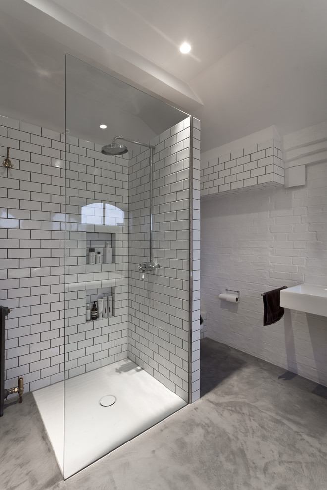 Inspiration for a contemporary bathroom in London with white tile, subway tile, a curbless shower, a wall-mount sink, white walls and concrete floors.