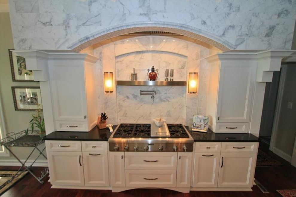 Mid-sized transitional u-shaped dark wood floor enclosed kitchen photo with a drop-in sink, flat-panel cabinets, white cabinets, granite countertops, white backsplash, stainless steel appliances and an island