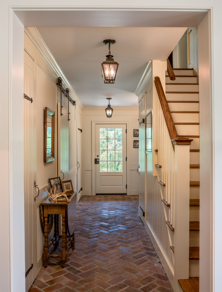 This is an example of a large traditional hallway in Philadelphia with beige walls, brick floors and red floor.