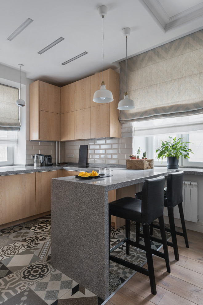 Mid-sized scandinavian u-shaped eat-in kitchen in Moscow with an undermount sink, flat-panel cabinets, medium wood cabinets, solid surface benchtops, white splashback, ceramic splashback, stainless steel appliances, ceramic floors, with island, grey floor, grey benchtop and recessed.