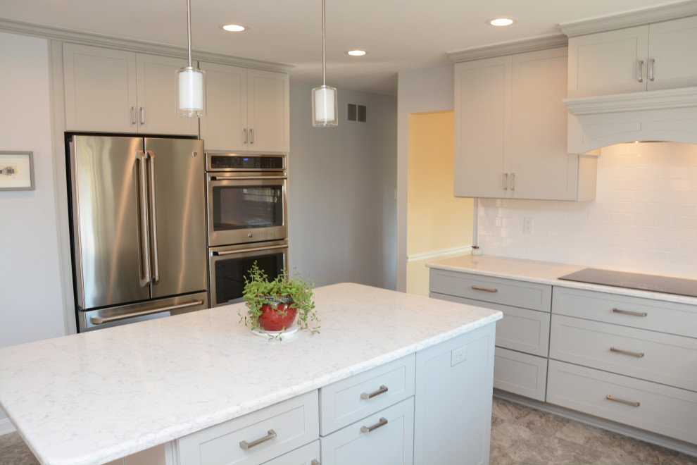 Inspiration for a mid-sized transitional l-shaped open plan kitchen in DC Metro with a single-bowl sink, recessed-panel cabinets, grey cabinets, quartz benchtops, white splashback, subway tile splashback, stainless steel appliances, with island, grey floor and white benchtop.