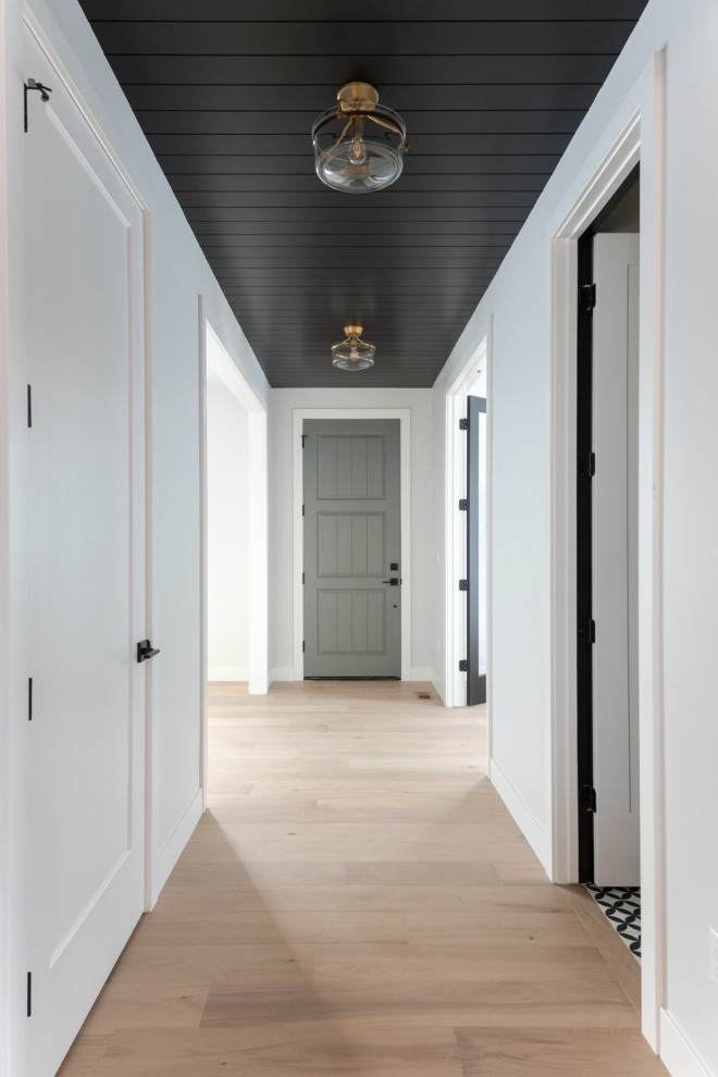 Immagine di una porta d'ingresso chic con pareti bianche, parquet chiaro, una porta singola, una porta grigia e soffitto in perlinato