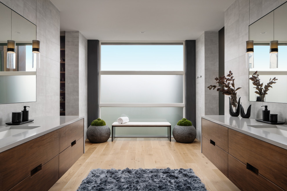 Design ideas for a contemporary ensuite bathroom in Austin with flat-panel cabinets, dark wood cabinets, grey tiles, light hardwood flooring, a submerged sink, beige floors, double sinks, a floating vanity unit, grey walls, white worktops and an enclosed toilet.