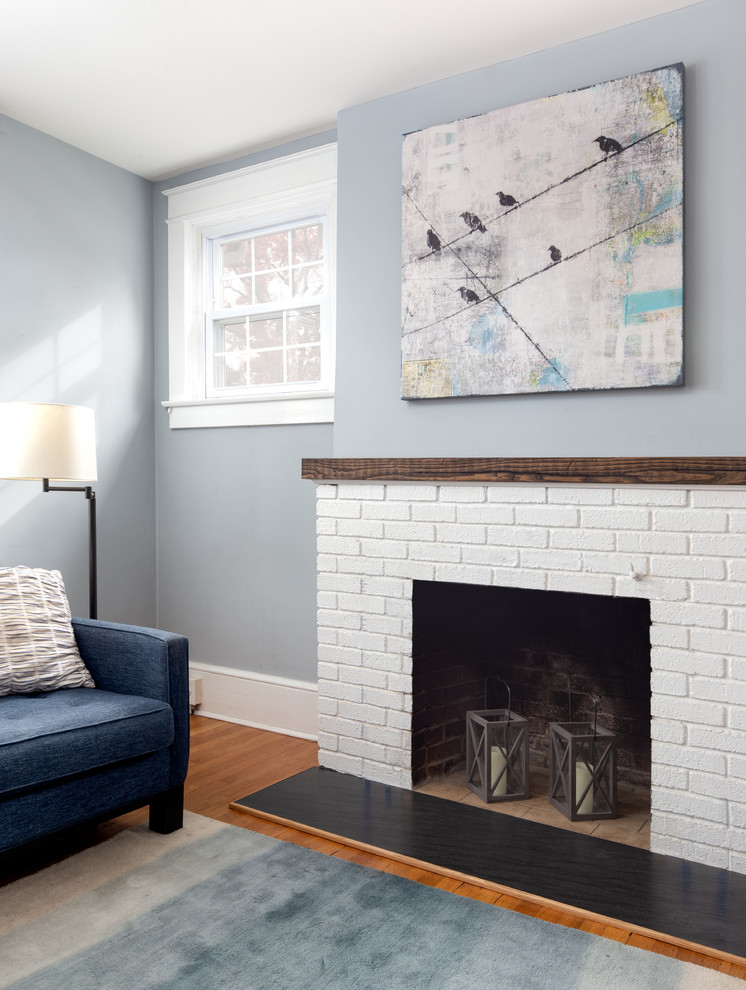 Inspiration for a mid-sized open concept family room in DC Metro with blue walls, medium hardwood floors, a standard fireplace, a brick fireplace surround and brown floor.