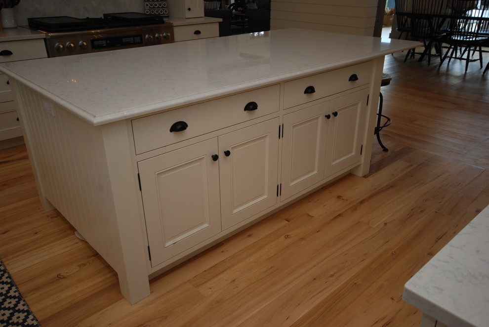 This is an example of a large traditional u-shaped eat-in kitchen in Ottawa with beaded inset cabinets, white cabinets, quartz benchtops, with island and light hardwood floors.