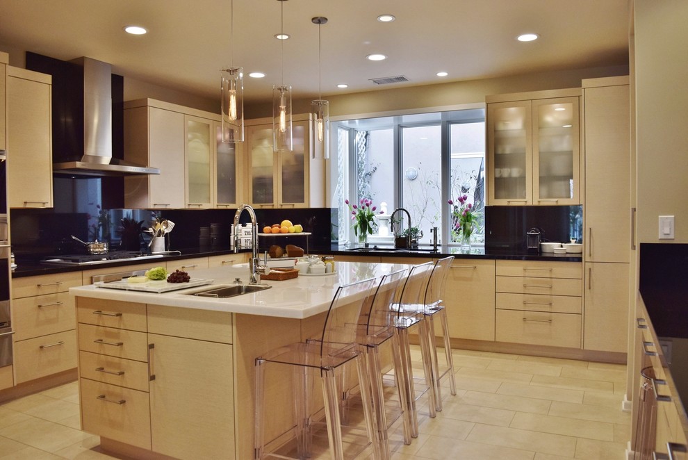 This is an example of a large contemporary u-shaped eat-in kitchen in Los Angeles with an undermount sink, glass-front cabinets, quartzite benchtops, black splashback, stone slab splashback, stainless steel appliances, porcelain floors, with island and beige cabinets.