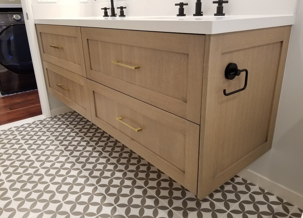 Photo of a mid-sized modern 3/4 bathroom in Los Angeles with shaker cabinets, light wood cabinets, an alcove tub, a shower/bathtub combo, a one-piece toilet, ceramic tile, beige walls, porcelain floors, an undermount sink, solid surface benchtops, multi-coloured floor, a hinged shower door and beige benchtops.