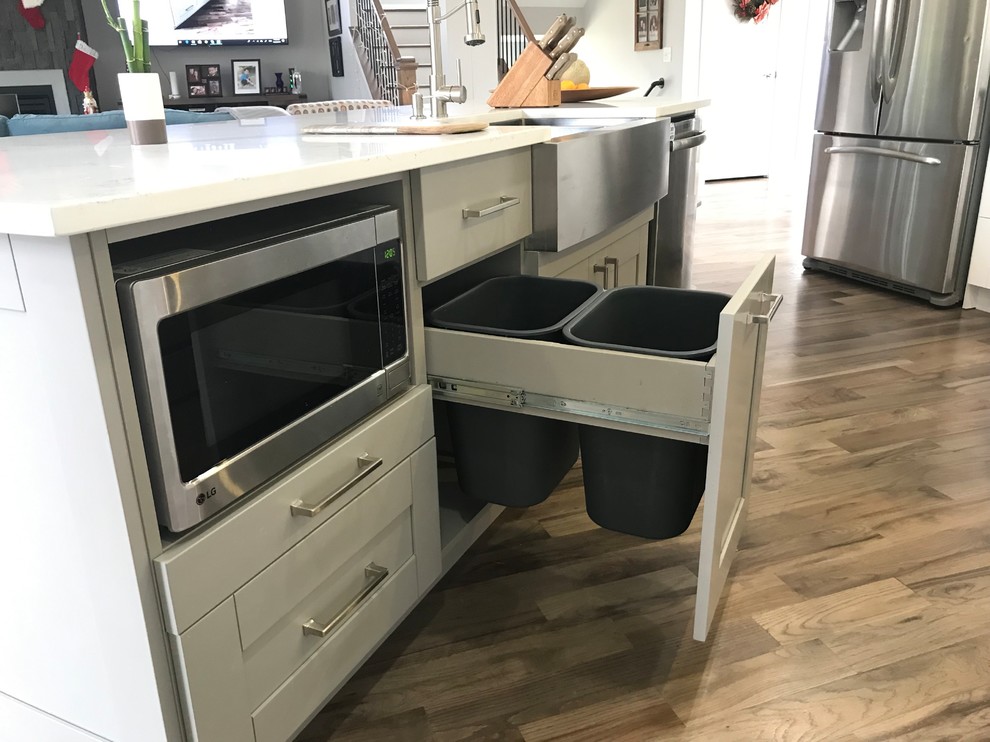Example of a large transitional single-wall light wood floor and gray floor eat-in kitchen design in Atlanta with a farmhouse sink, shaker cabinets, white cabinets, quartzite countertops, white backsplash, marble backsplash, stainless steel appliances, an island and white countertops