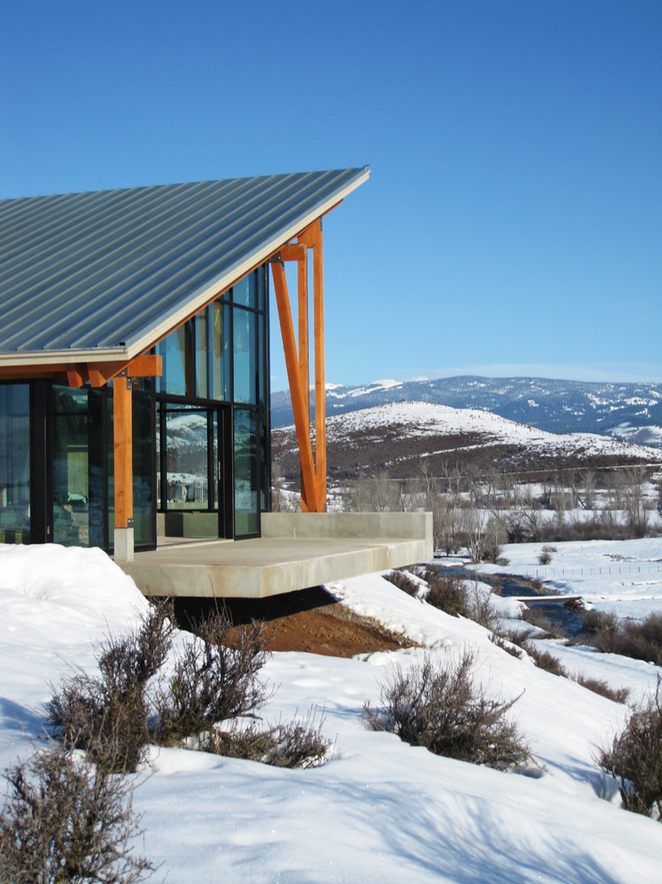 This is an example of an expansive modern one-storey glass house exterior in Boise with a shed roof and a metal roof.