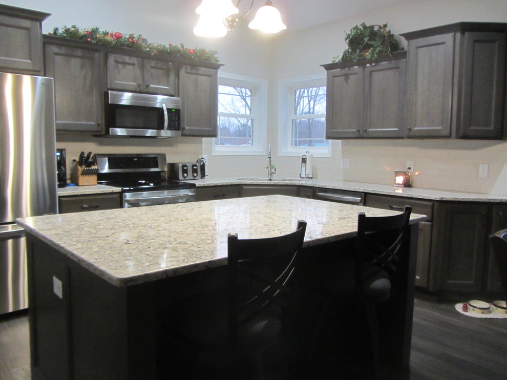 Inspiration for a mid-sized transitional l-shaped medium tone wood floor and gray floor open concept kitchen remodel with an undermount sink, flat-panel cabinets, gray cabinets, quartz countertops, white backsplash, stainless steel appliances and an island