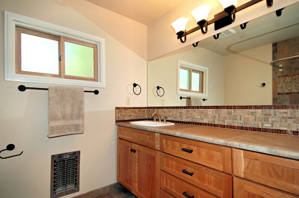 This is an example of a mid-sized asian master bathroom in Portland with shaker cabinets, light wood cabinets, a shower/bathtub combo, beige walls, a drop-in sink, a shower curtain, a one-piece toilet, beige tile, black tile, brown tile and dark hardwood floors.
