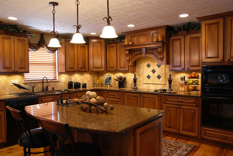 Mid-sized elegant l-shaped dark wood floor and brown floor eat-in kitchen photo in Philadelphia with a double-bowl sink, raised-panel cabinets, dark wood cabinets, granite countertops, beige backsplash, stone tile backsplash, black appliances and an island