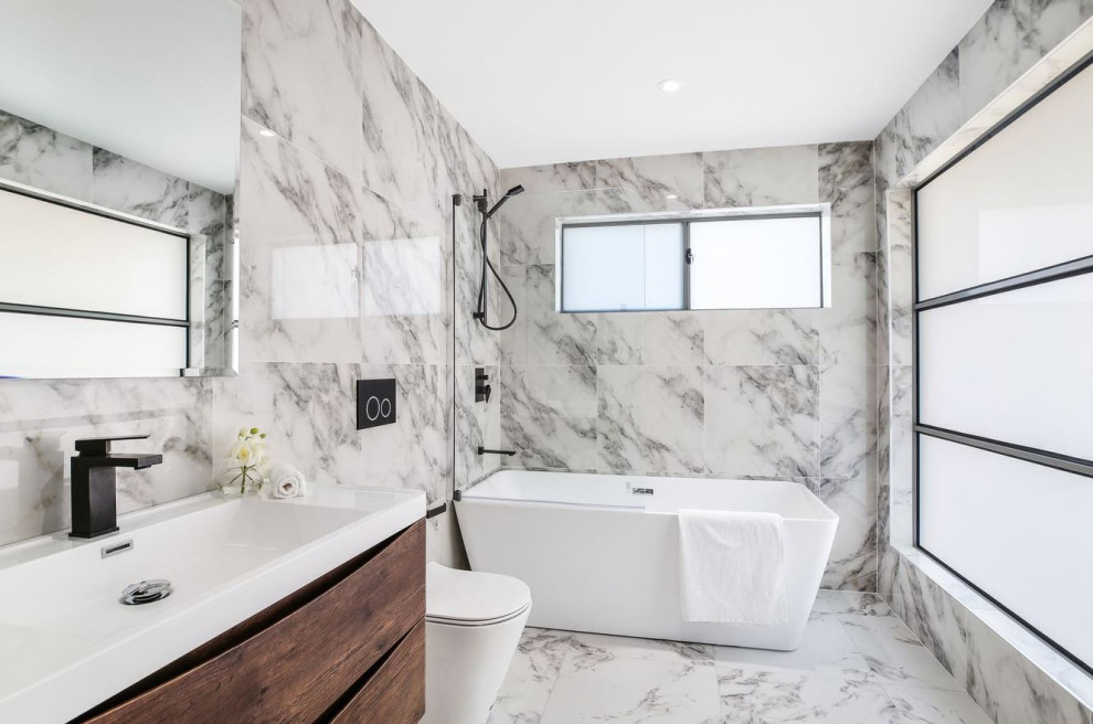 Large contemporary master bathroom in Sydney with brown cabinets, a freestanding tub, a shower/bathtub combo, a one-piece toilet, black and white tile, marble, marble floors, a drop-in sink, solid surface benchtops, a hinged shower door, white benchtops, a single vanity and a floating vanity.