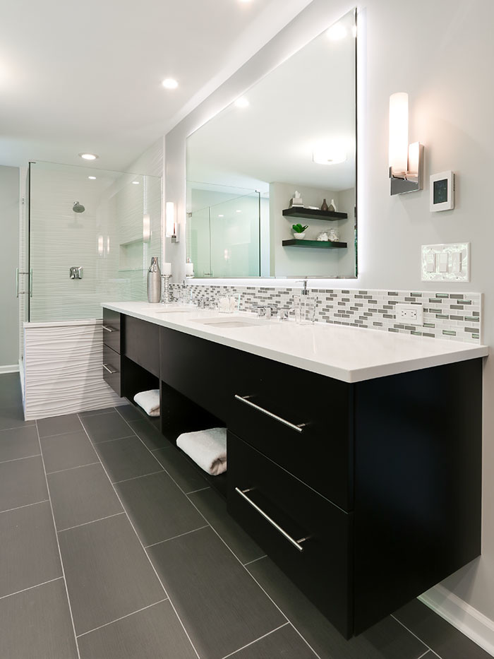 Inspiration for a large contemporary master bathroom in Chicago with flat-panel cabinets, dark wood cabinets, a drop-in tub, an open shower, a one-piece toilet, multi-coloured tile, glass tile, beige walls, porcelain floors, an undermount sink and engineered quartz benchtops.