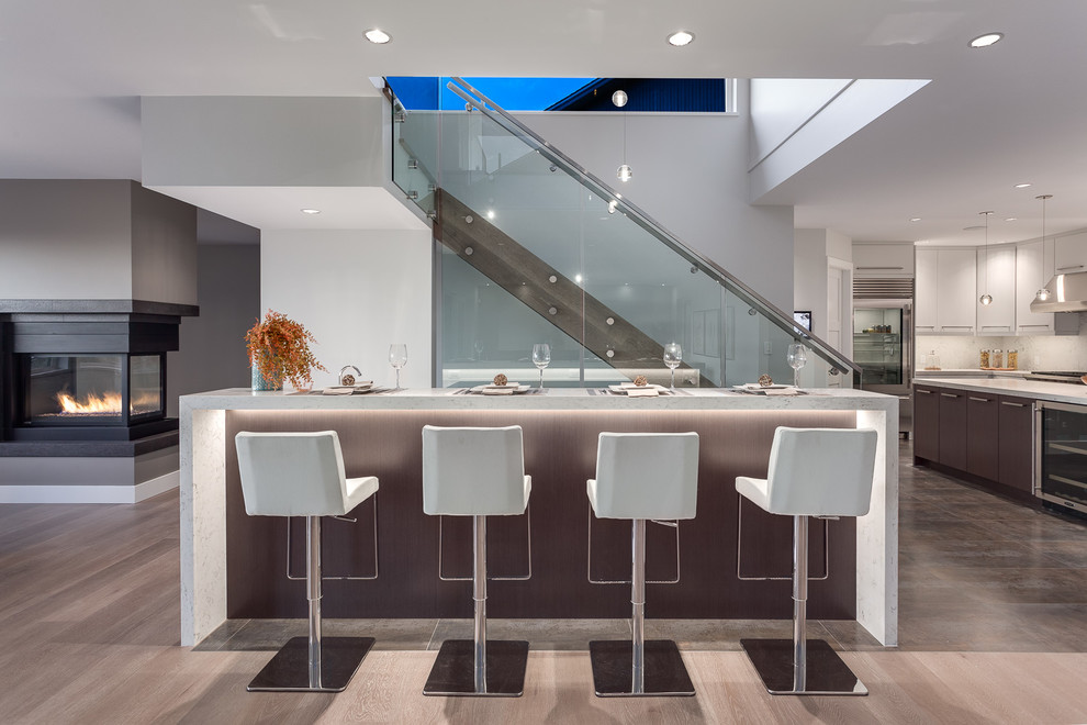 Large contemporary seated home bar in Vancouver with flat-panel cabinets, dark wood cabinets, quartzite benchtops, white splashback, stone slab splashback, porcelain floors and white benchtop.